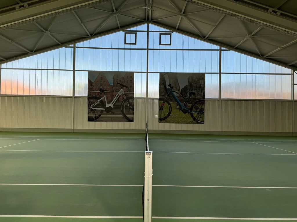 Badmintonhalle Berwangen mit mehreren Spielfeldern und zwei Bildern mit E-Bikes an der Wand